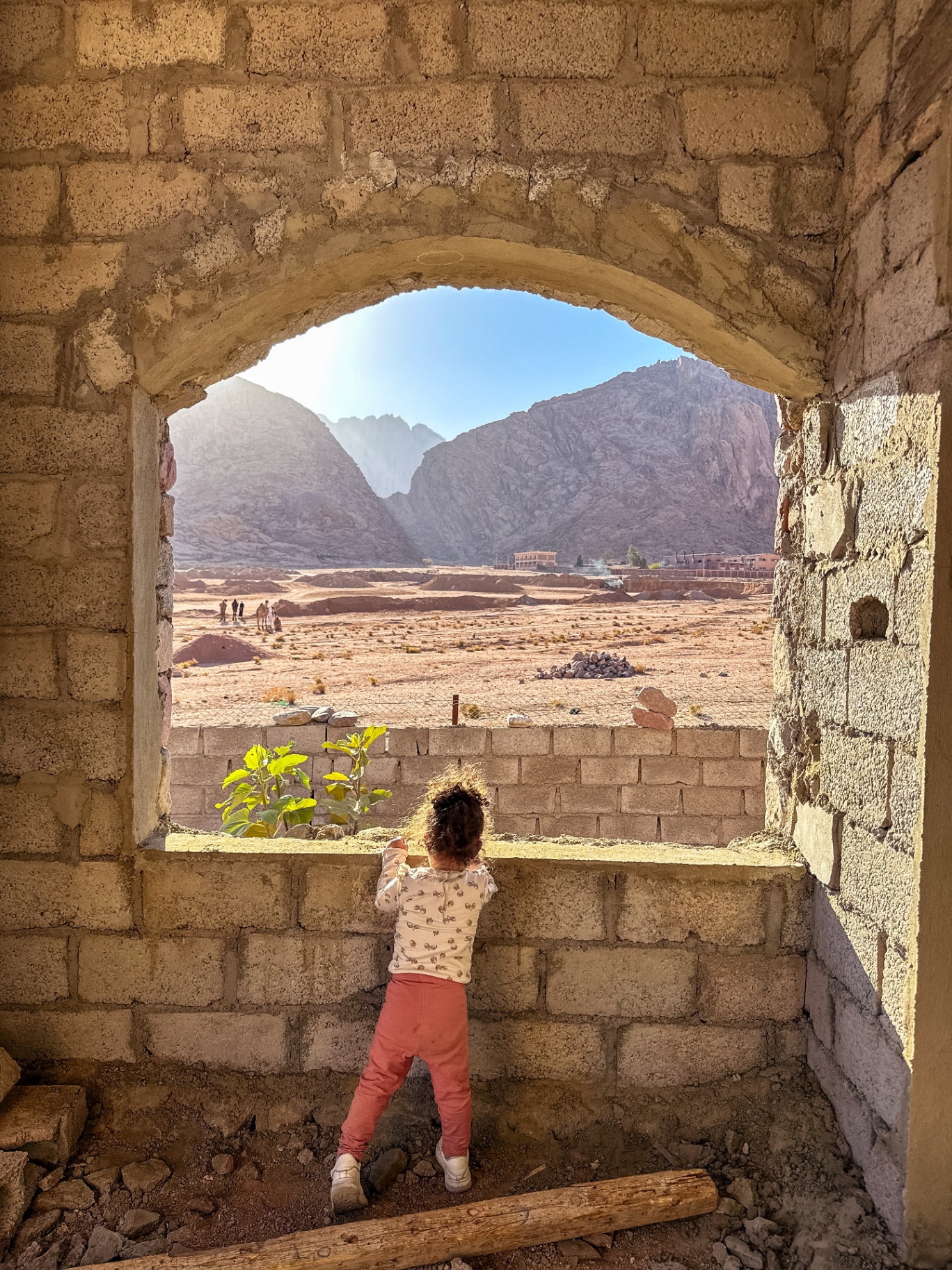 Child reaching towards arched window with mountain view at Dar Katrine